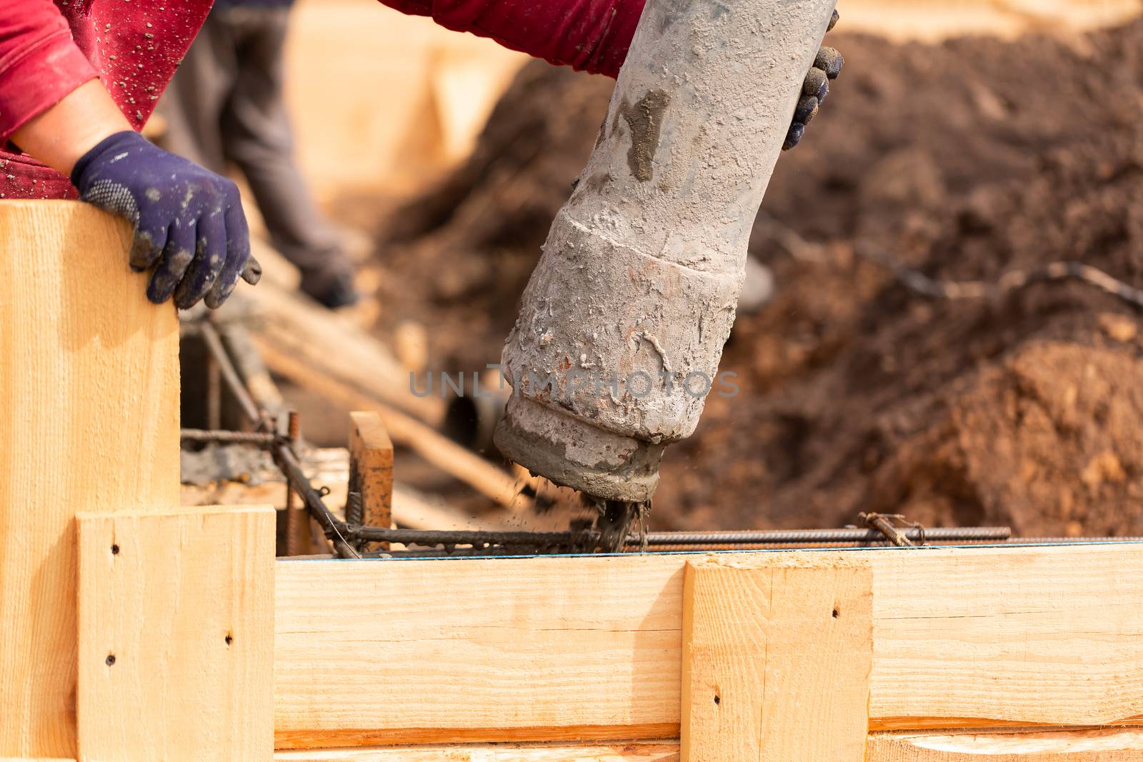 Close up of construction worker laying cement or concrete into the foundation formwork with automatic pump. Building house foundation