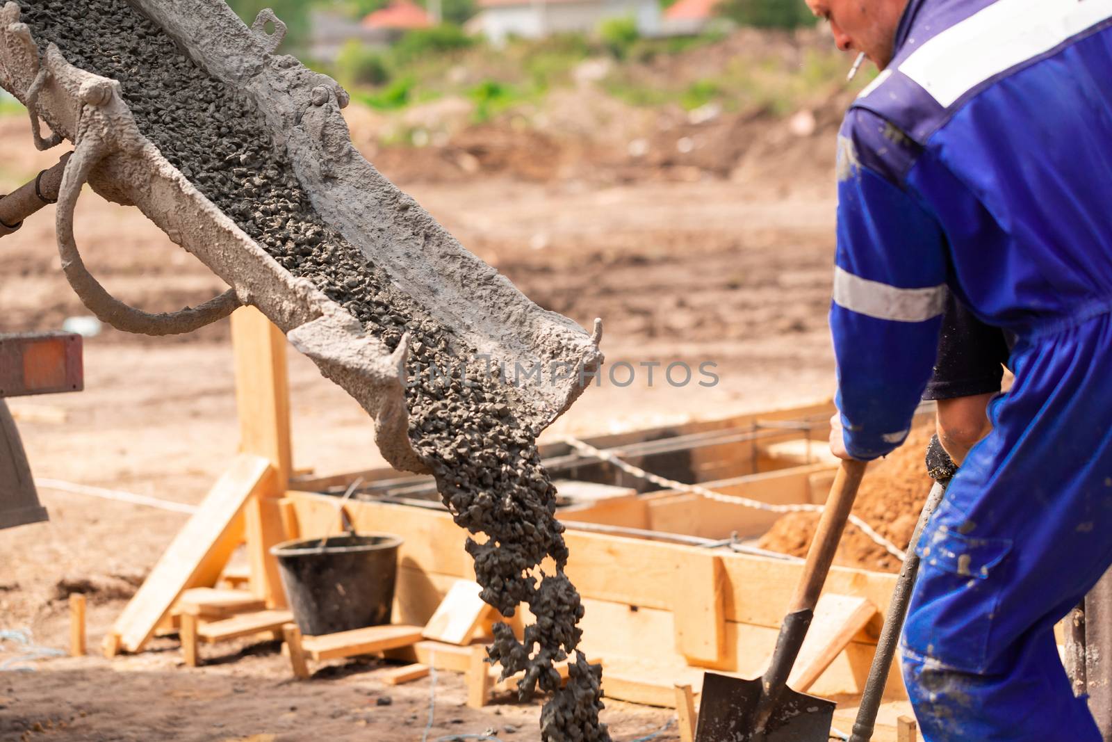 Construction worker laying cement or concrete into the foundation formwork with automatic pump. Building house foundation