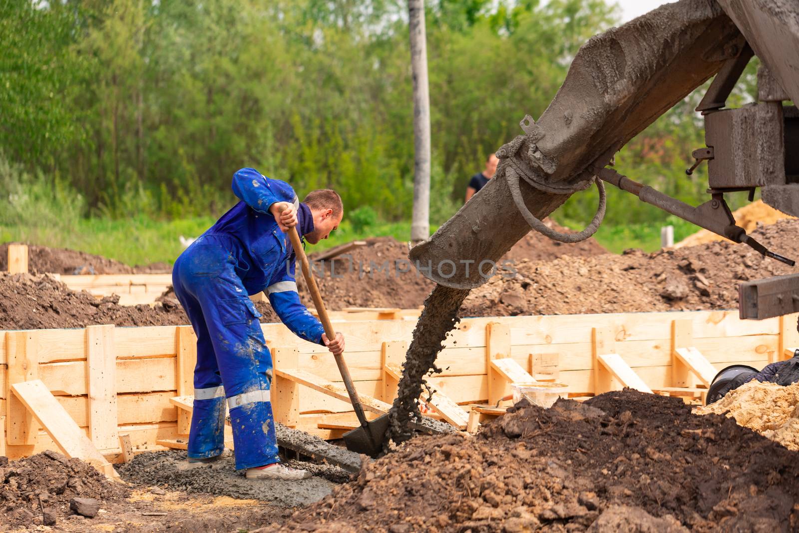 Construction worker laying cement or concrete into the foundation formwork. Building house foundation