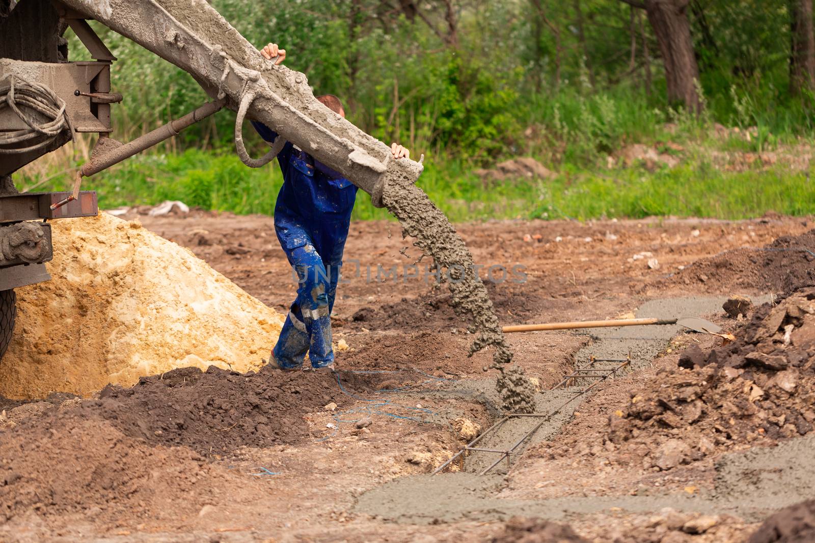 Construction worker laying cement or concrete into the foundation formwork. Building house foundation