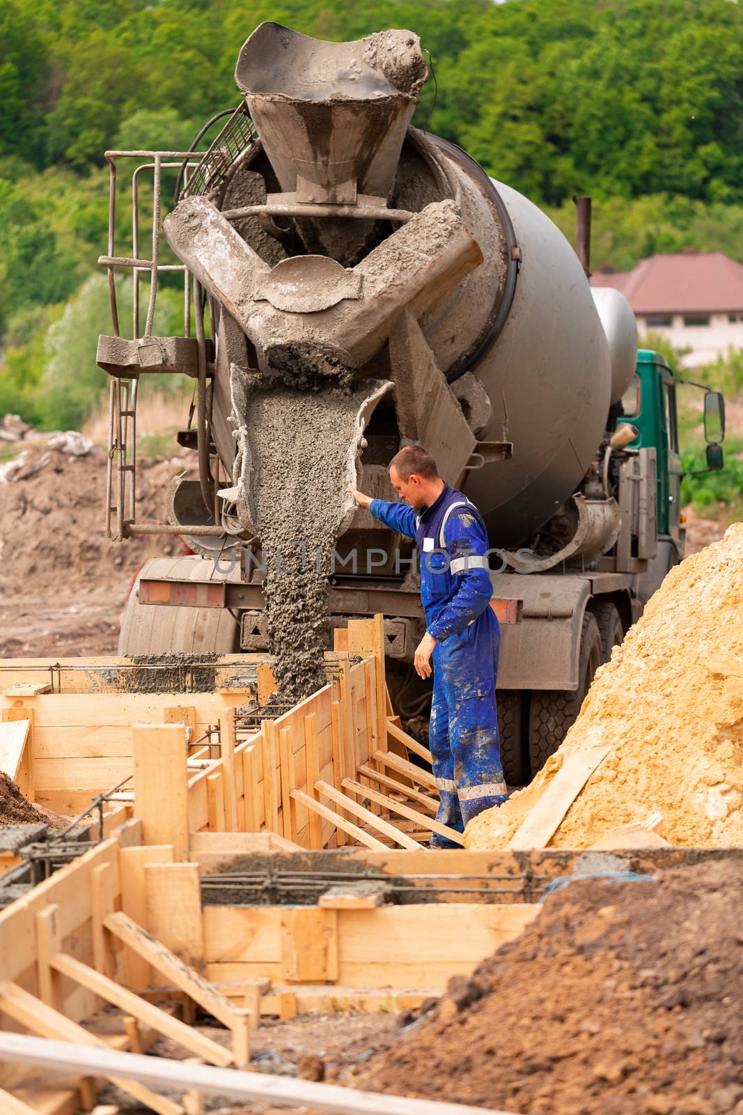 Construction worker laying cement or concrete into the foundation formwork. Building house foundation