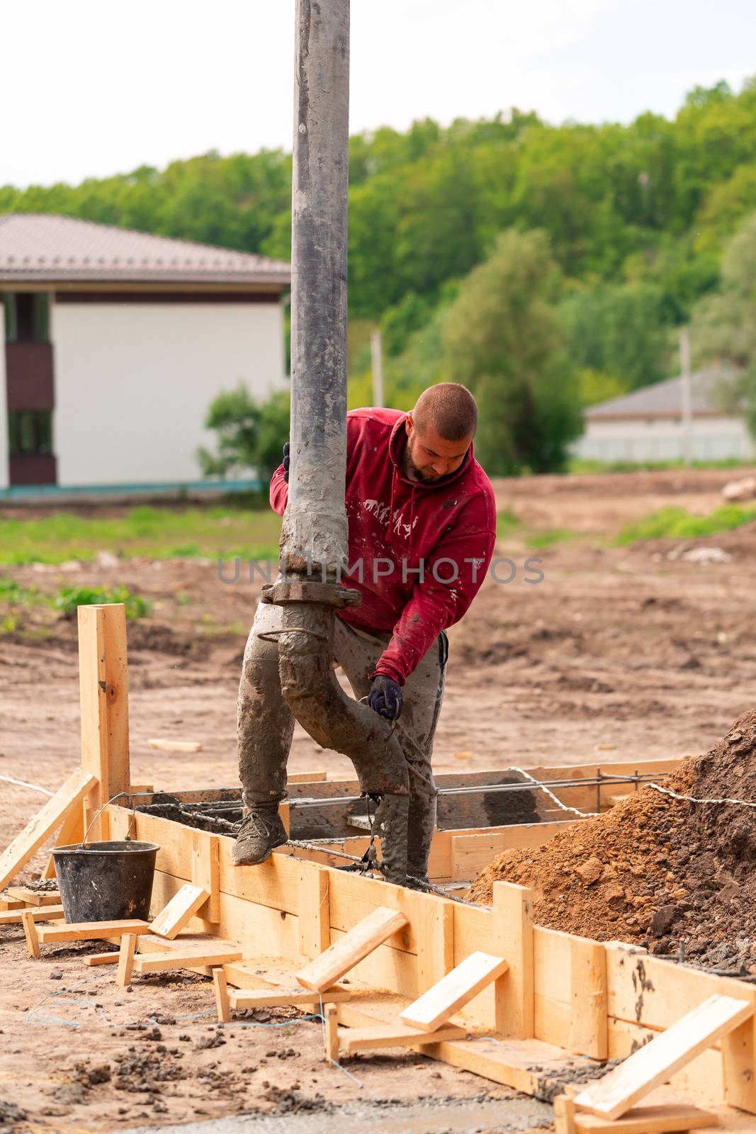 Construction worker laying cement or concrete into the foundation formwork with automatic pump by Len44ik