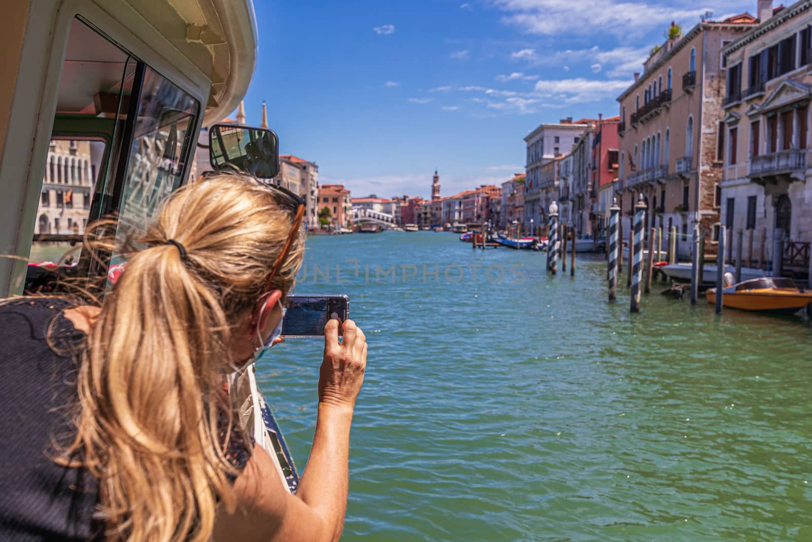 Woman with face mask taking picture of Grand canal in Venice, Italy by COffe