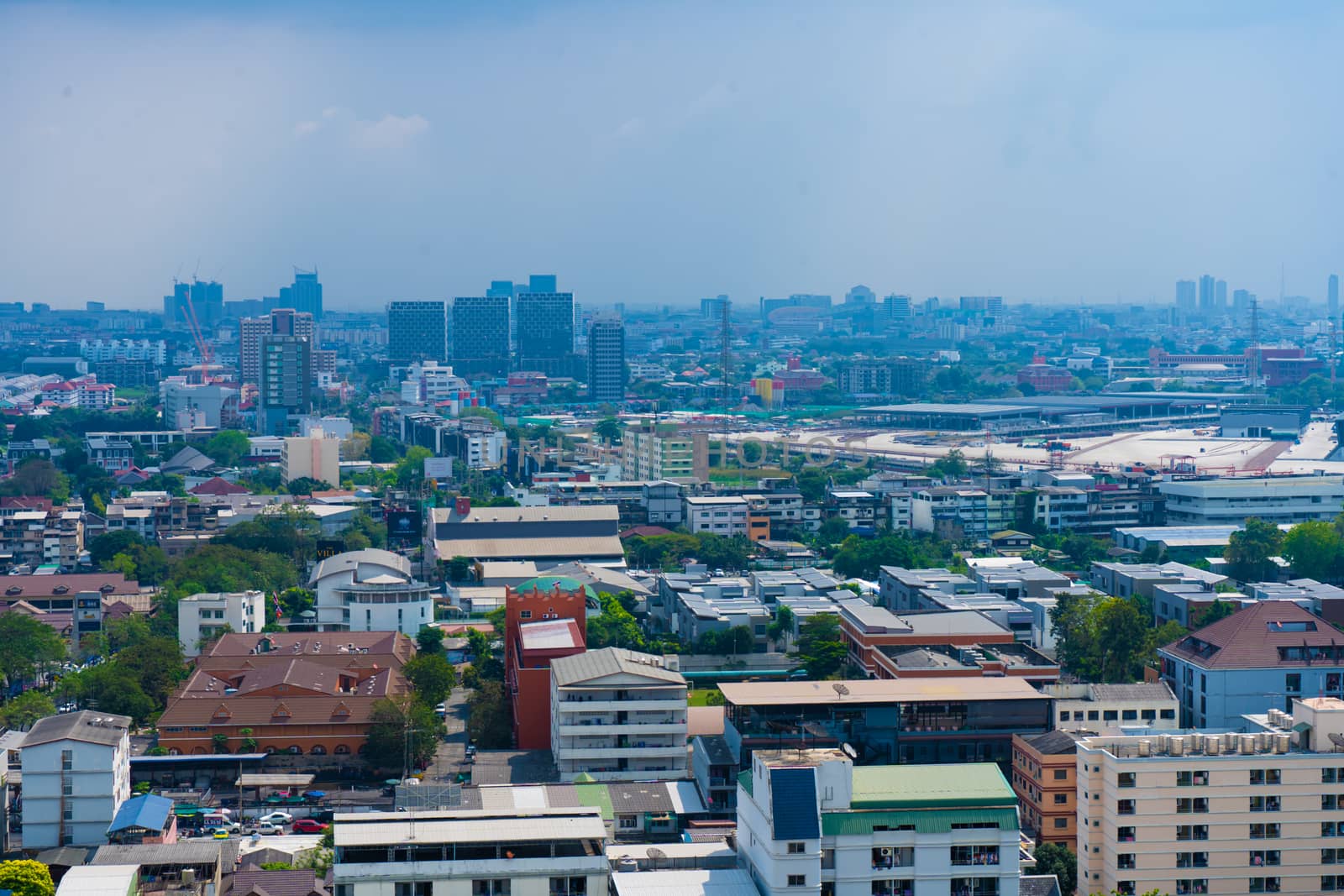 View from the high floor of the streets of Bangkok. Tall buildings and roofs of small houses. City landscape.