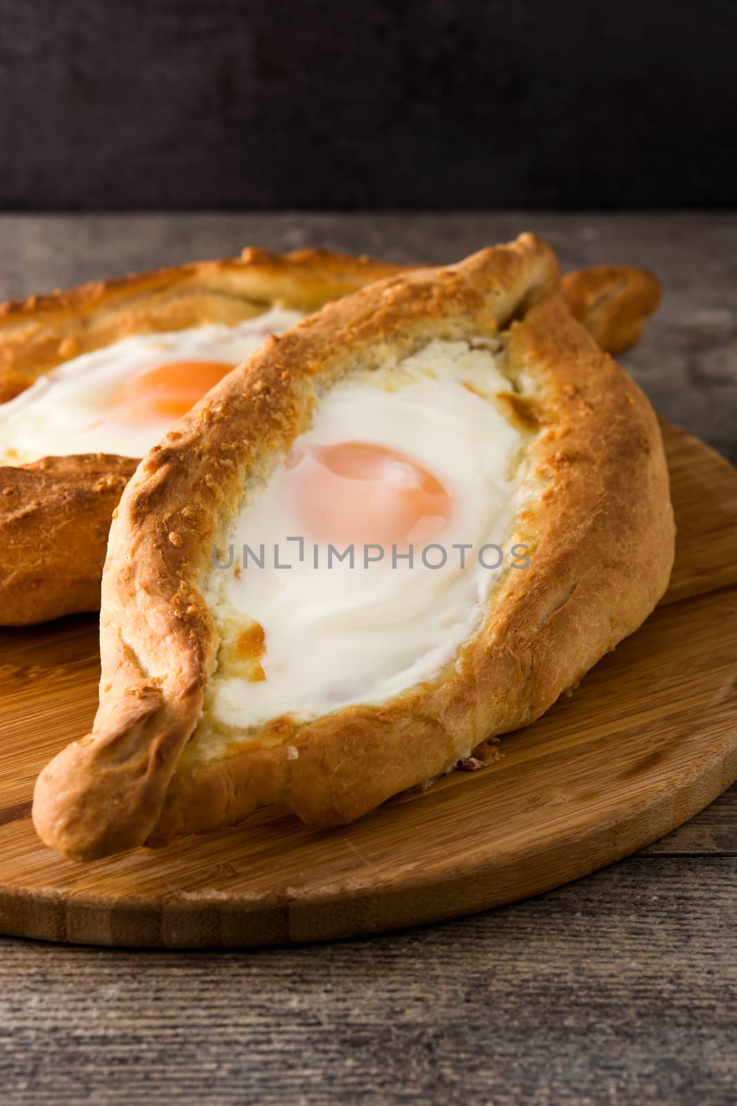 Traditional Adjarian Georgian khachapuri with cheese and egg on wooden table by chandlervid85