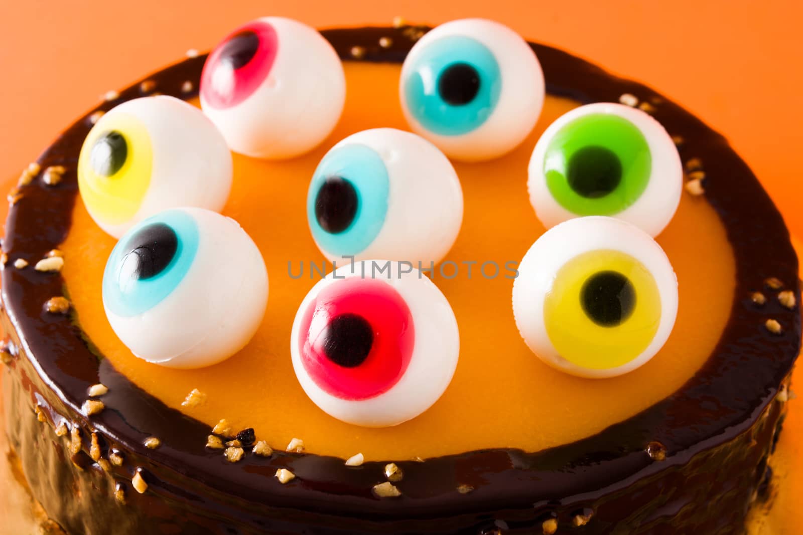 Halloween cake with candy eyes decoration isolated on orange background.