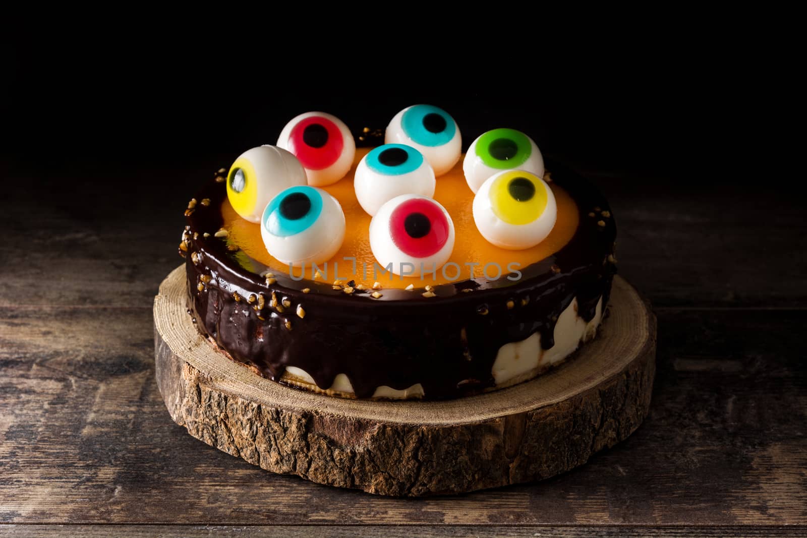 Halloween cake with candy eyes decoration on wooden table by chandlervid85