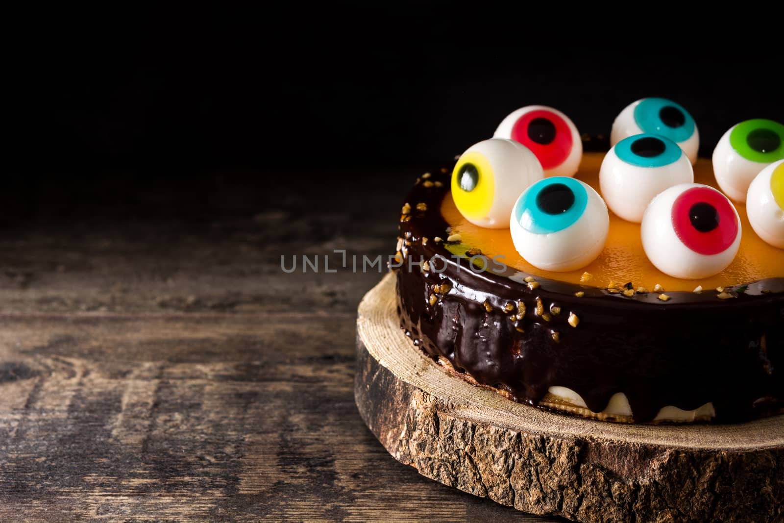 Halloween cake with candy eyes decoration on wooden table