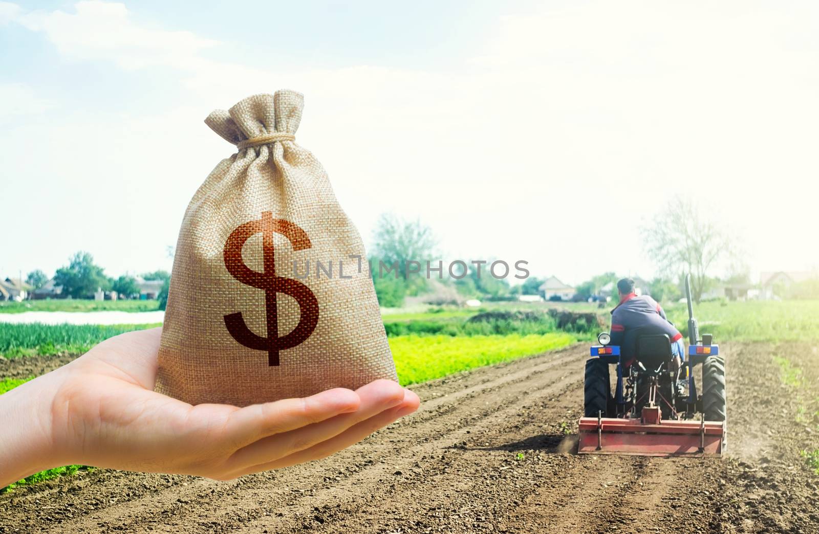 A hand holds out a dollar money bag on a background of a field cultivating tractor. Lending farmers for purchase land and seed material, modernization. Support and subsidies. by iLixe48