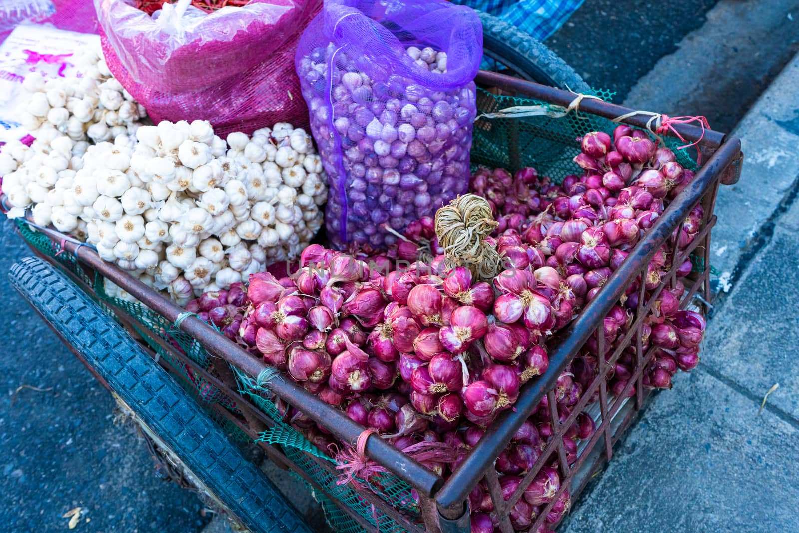Asian street vendor sells seasonings, onions, garlic and peppers on a cart on the street