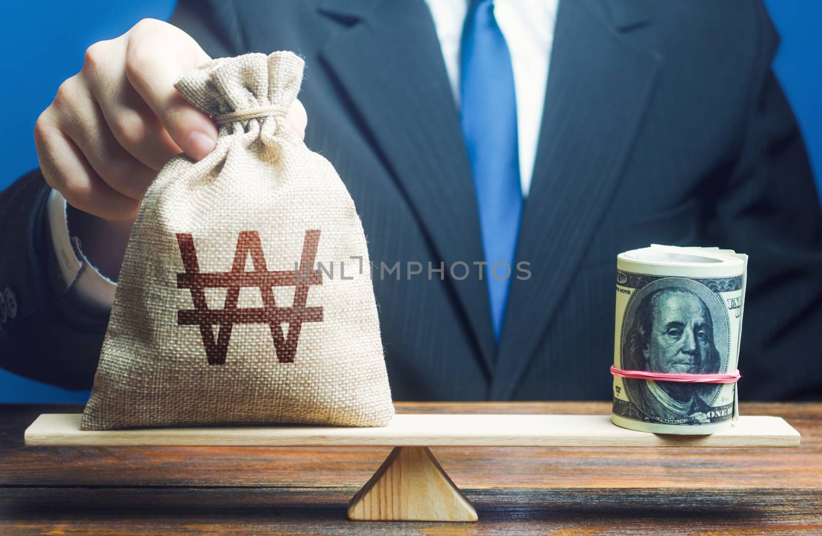 A man puts south korean won money bag on the scales opposite to the dollar. Protecting savings from inflation. Exchange rate, comparison of economic indicators. Investments in foreign currency bonds.