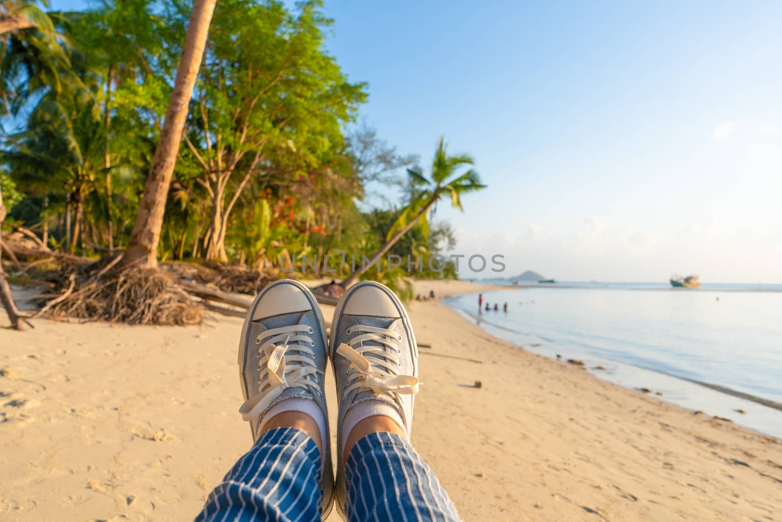 First-person view, a girl swinging on a swing on a sandy beach of a tropical island at sunset. Enjoys the vacation