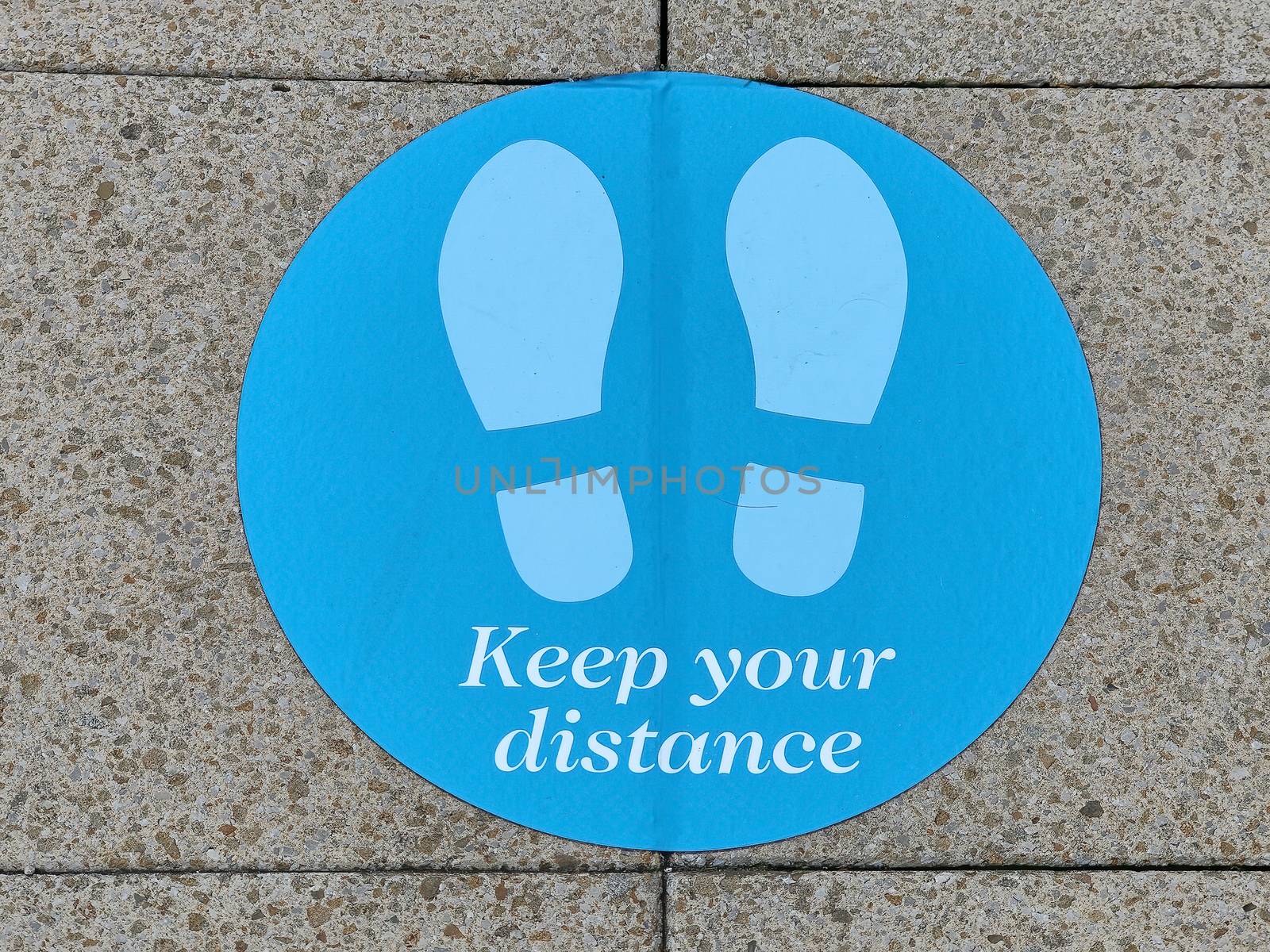 Keep your distance stand here sign on a pavement