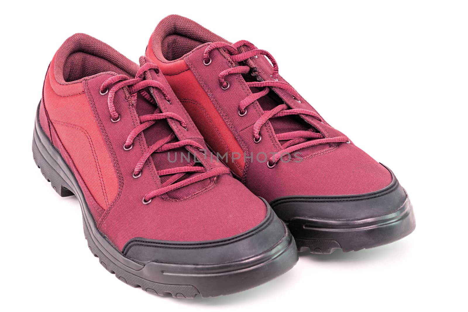 a pair of cheap cheap red hiking shoes isolated on white background - perspective close-up view.