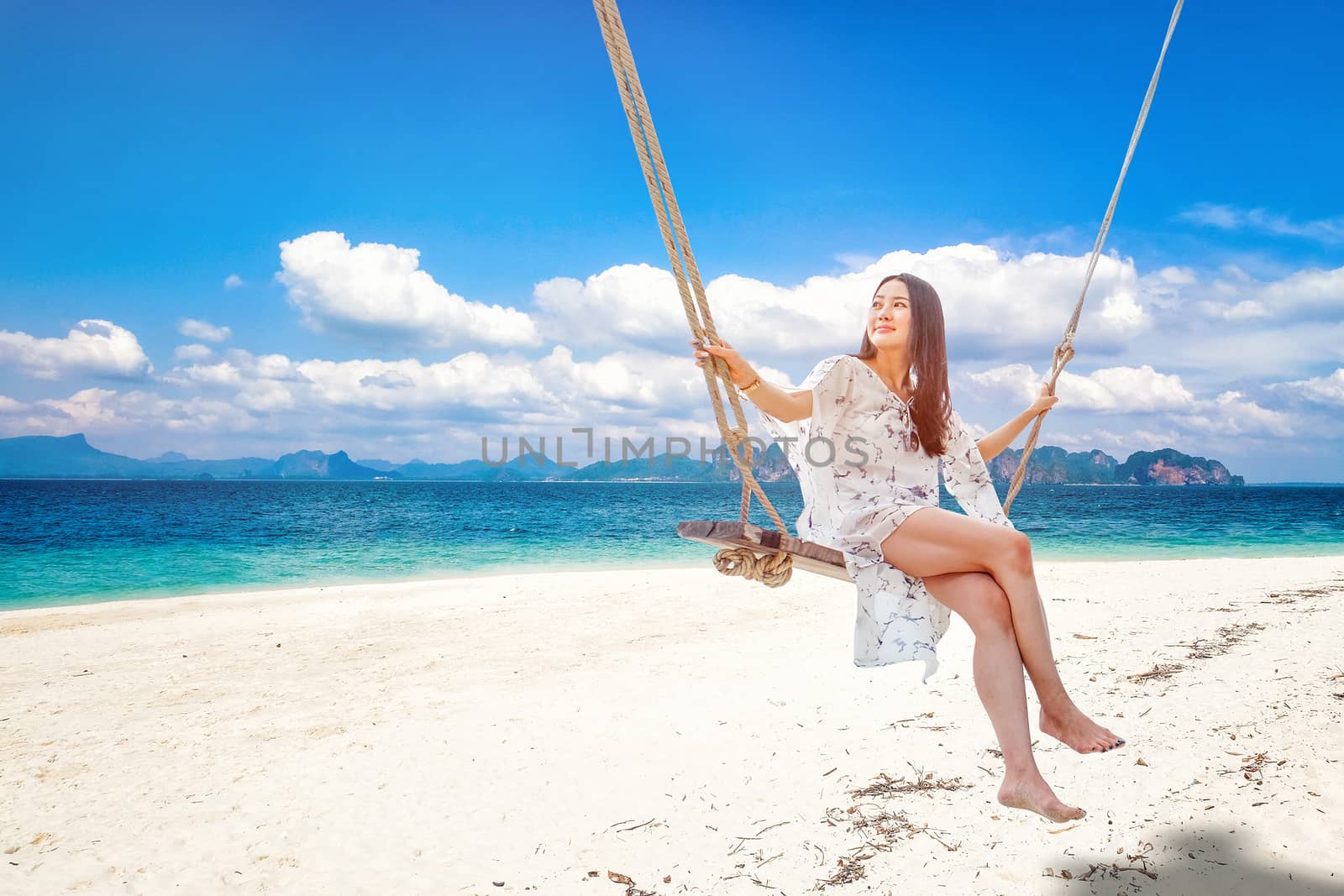 Beautiful woman sitting on a swing on the beach  in Krabi, Thailand