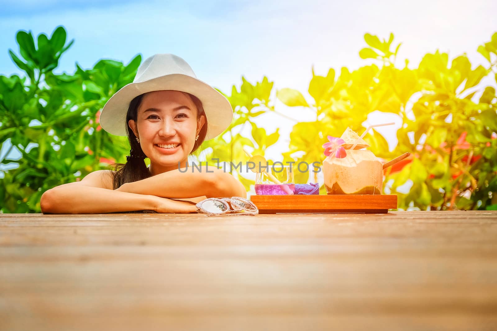 Happy woman with fresh coconut water on the beach by Surasak