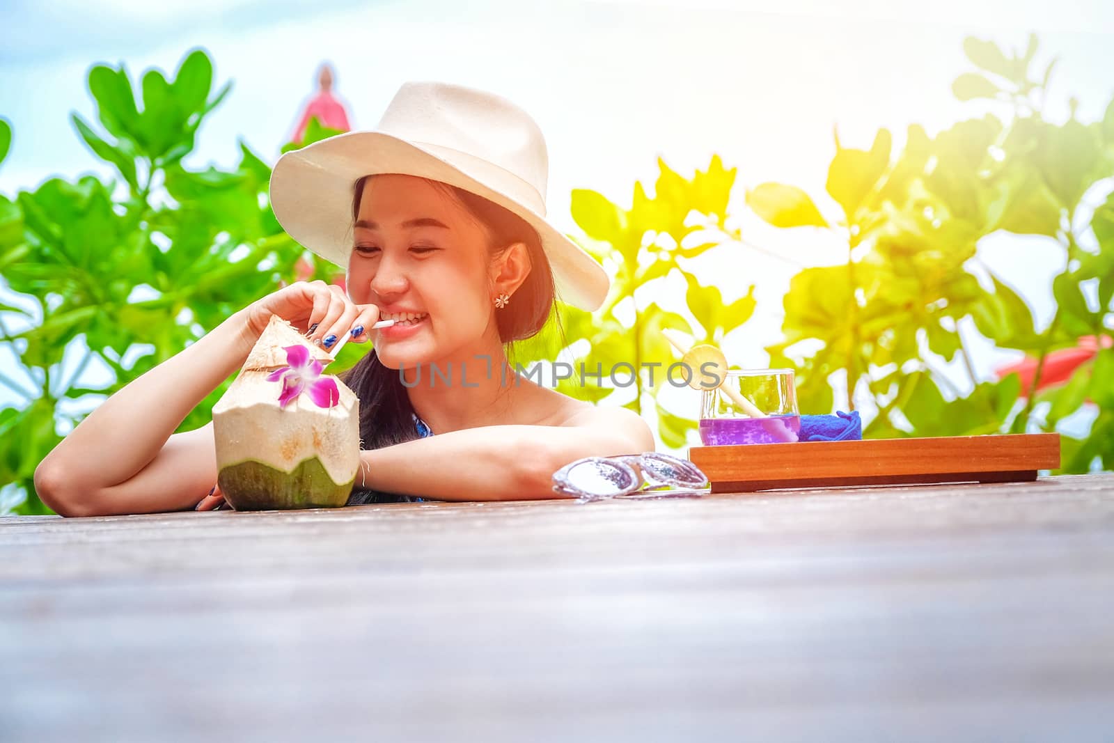 Happy woman with fresh coconut water on the beach by Surasak