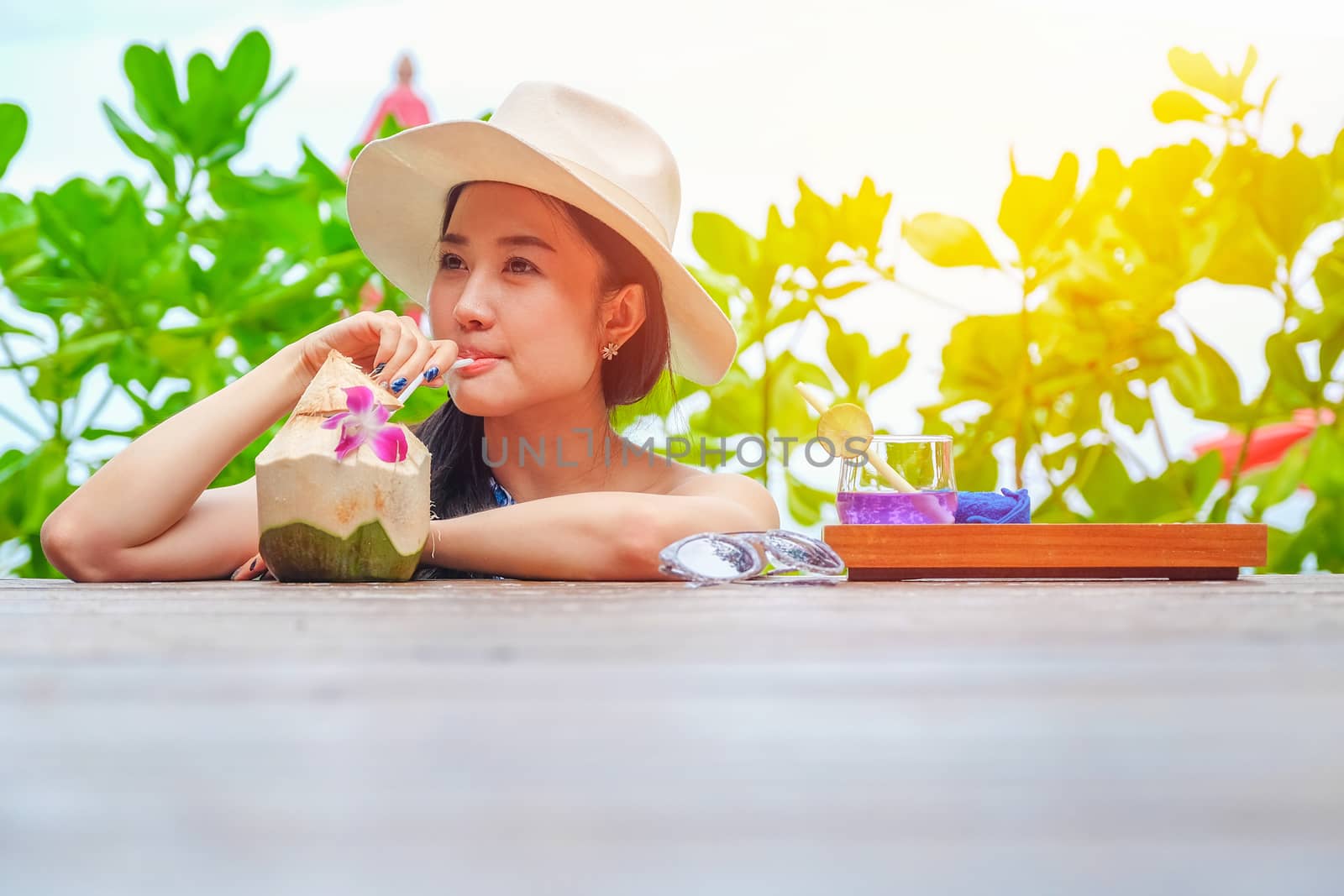 Happy woman with fresh coconut water on the beach by Surasak