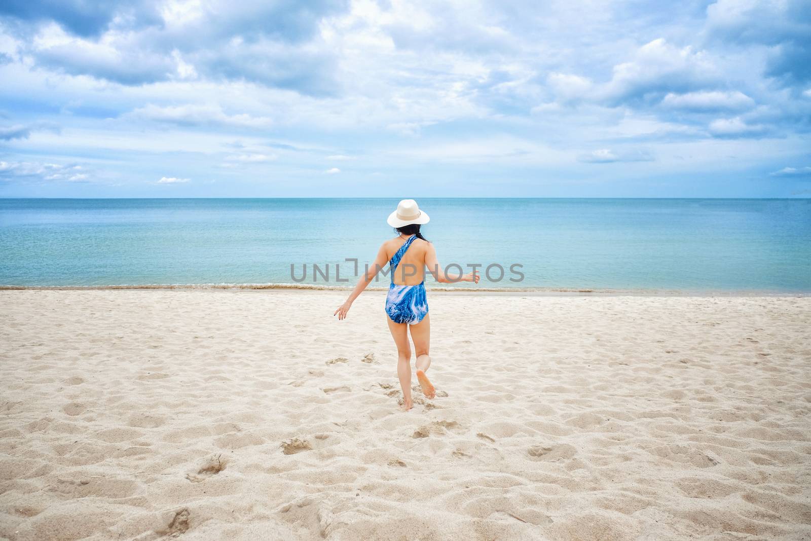 Young happy woman running on the beach 