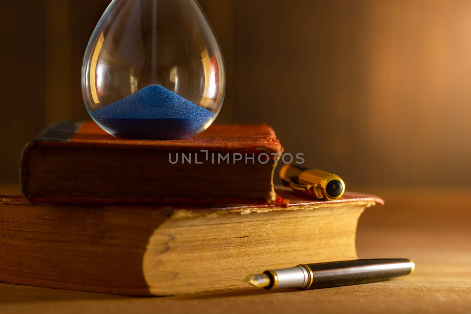 Hourglass on old book in morning light. Time of reading a book.