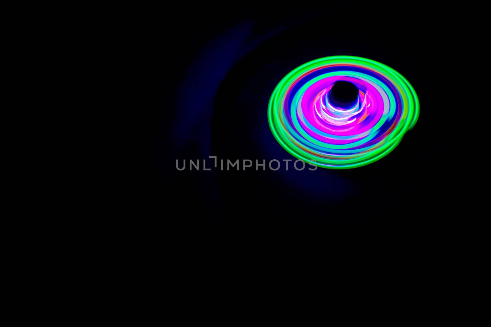 Long exposure photograph of a light spinning top with black background. by lalam