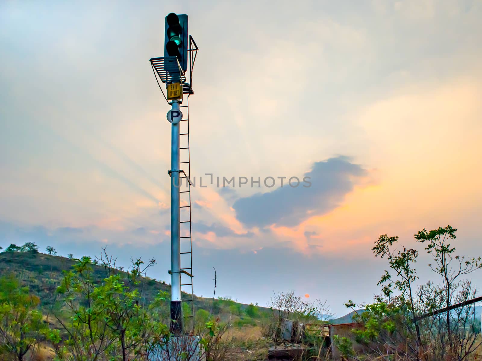 Railway signal post indicating green signal on a backdrop of beautiful evening Sunset and sky.