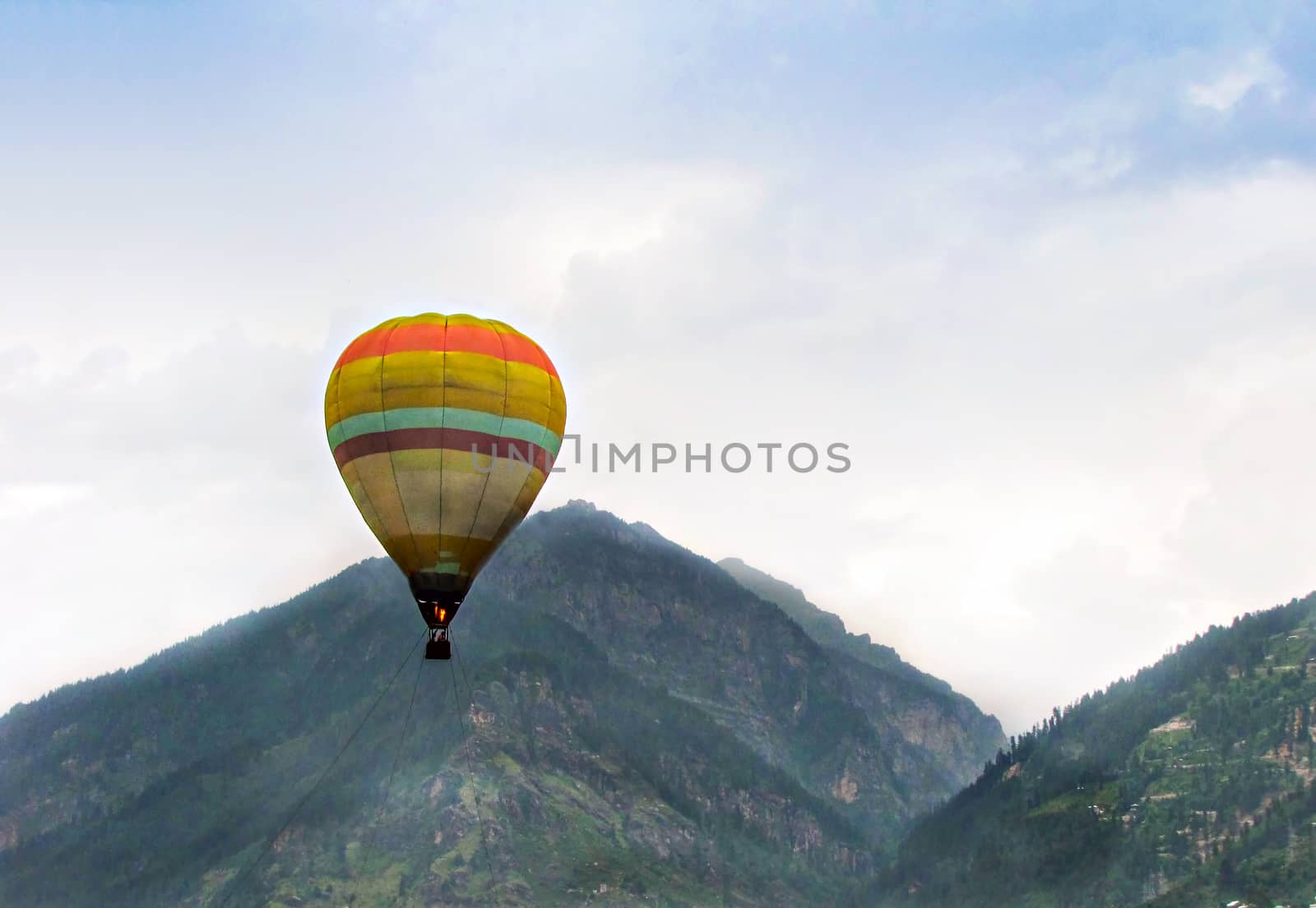 Isolated image of hot air balloon high in the air on a clear background of blue sky  in Manali, Himachal Pradesh, India.