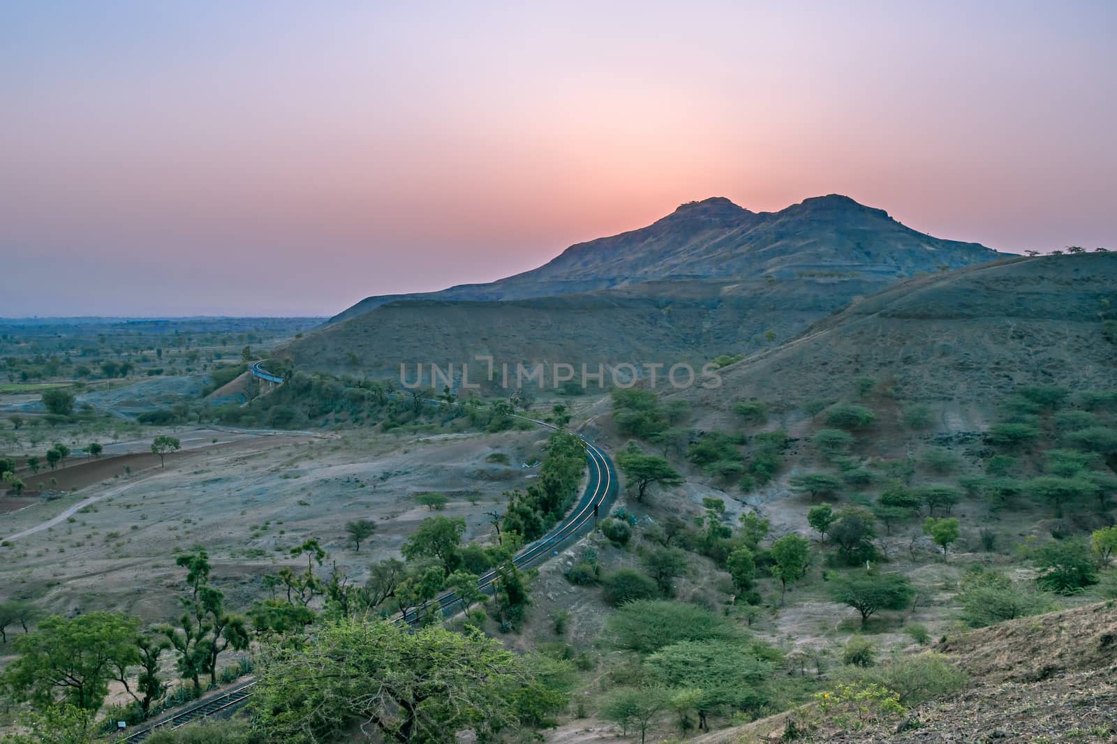 Rising Sun behind the hills along with a railway line in a village , outskirts of Pune, Maharashtra, India.