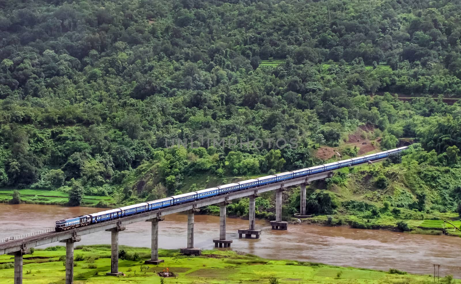 Scenic view of a train exiting tunnel and crossing bridge near Sangameshwar, India.