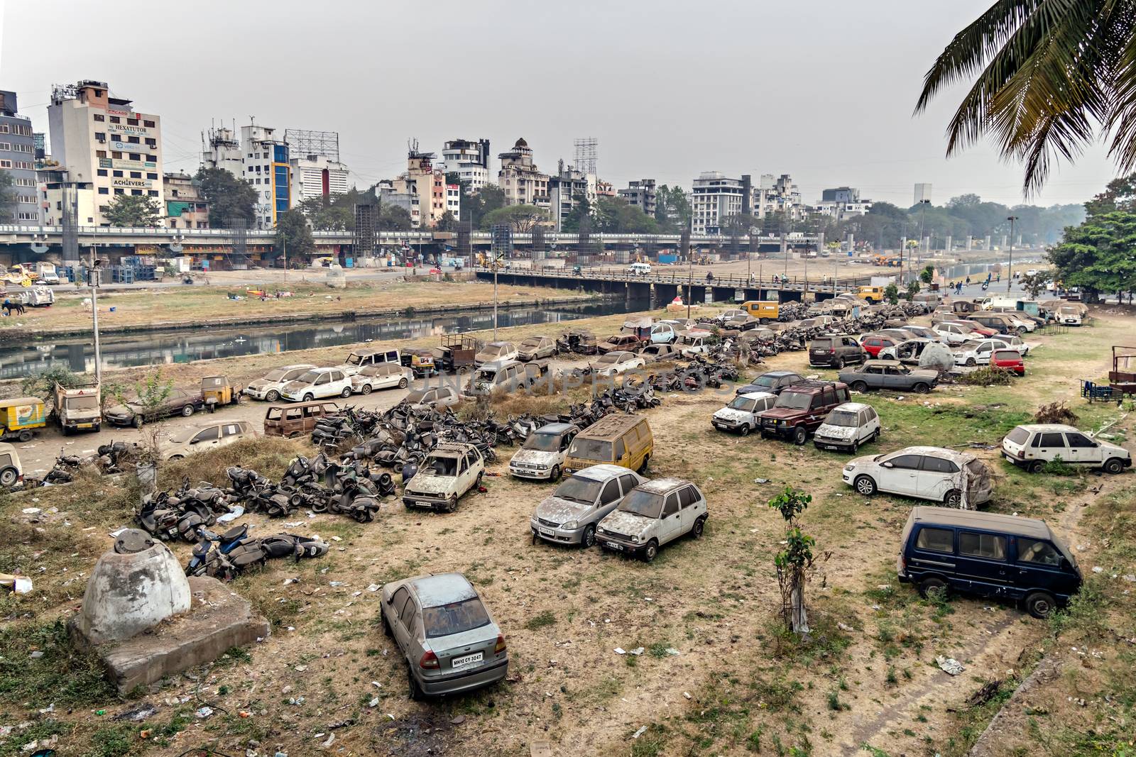 Old, abandoned, scrap vehicles scattered on the banks of Mutha river, Pune, Maharashtra, India.