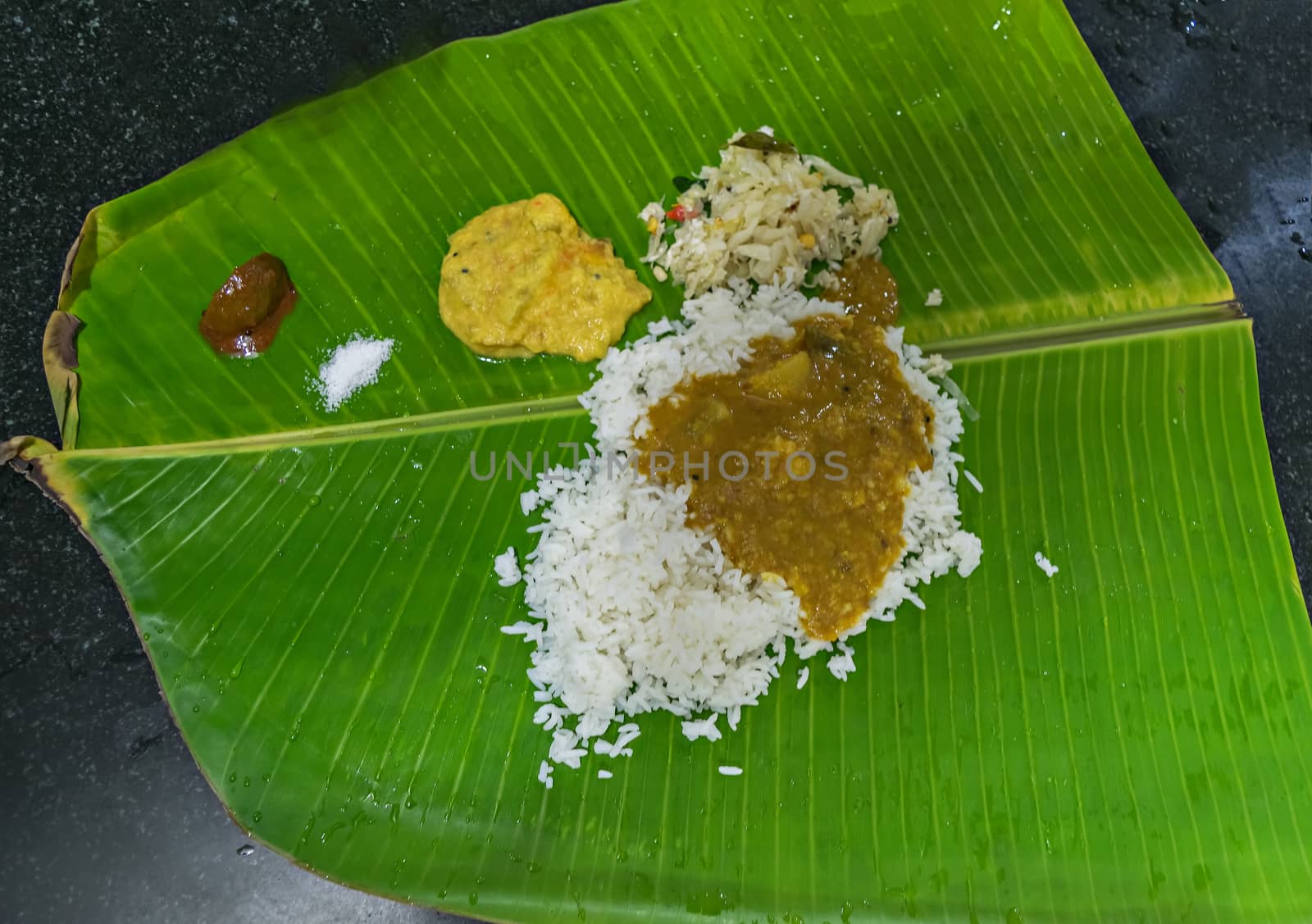 Authentic traditional south Indian meals served on banana leaf with rice, curry, pickle.. by lalam