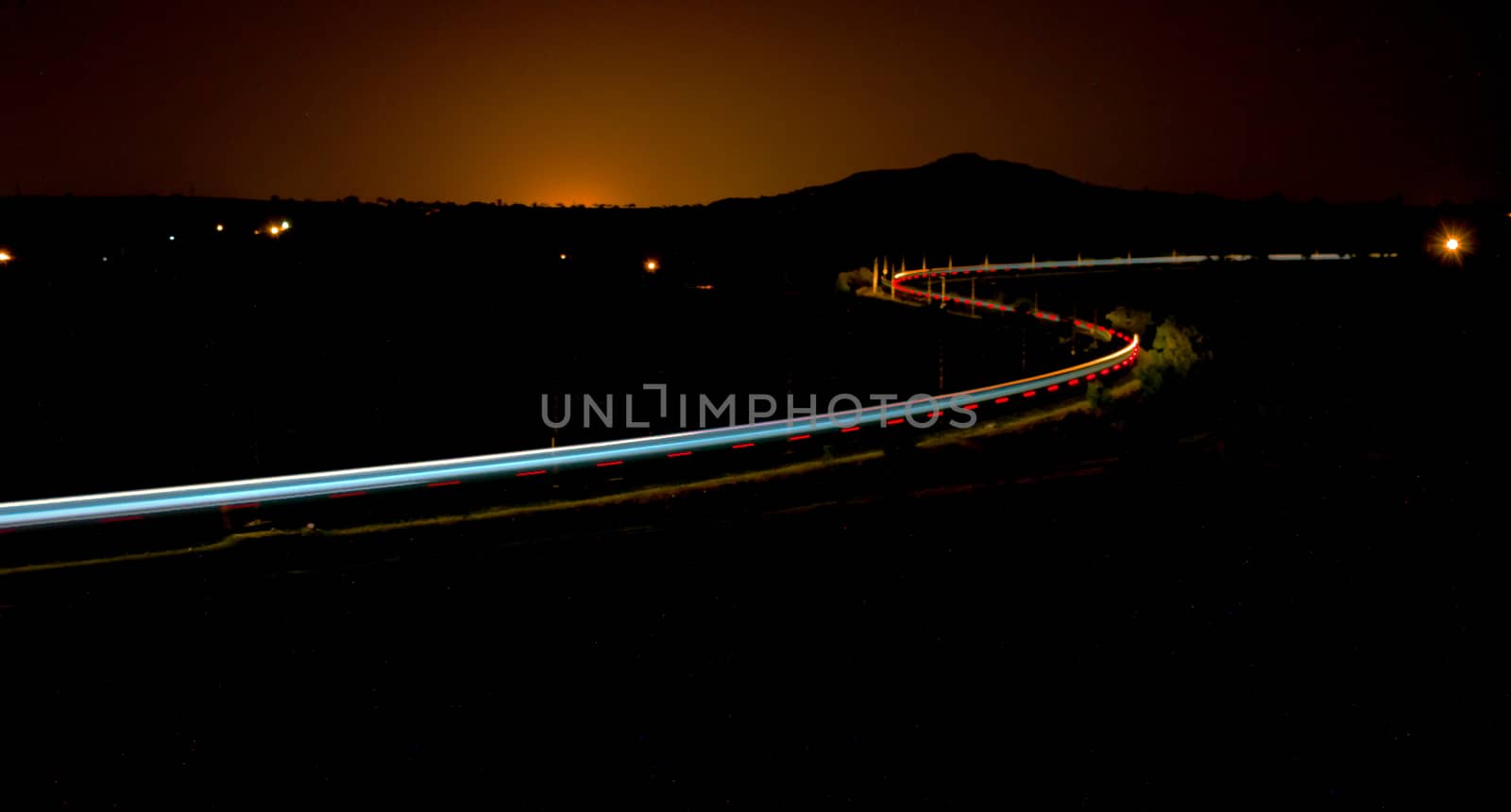 Long exposure slow shutter, colorful  photo of a train passing over s shaped rail track in Ranjangaon, Maharashtra, India.