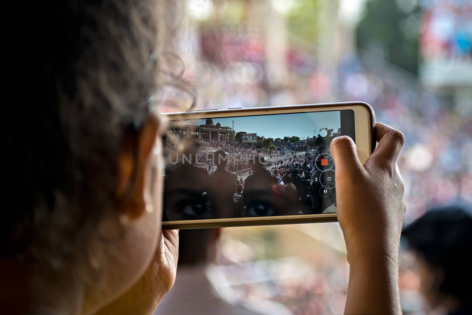 Young lady capturing video of beating retreat ceremony on her cell phone. in Attari, Amritsar, Punjab.