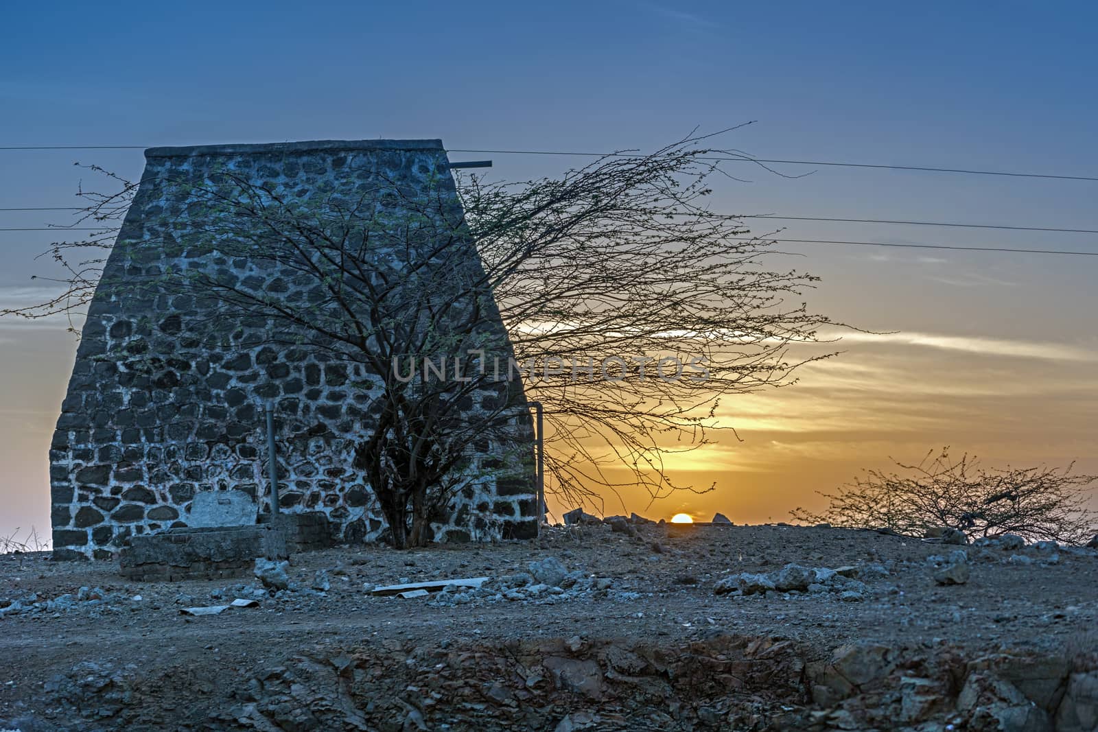 Sunrise behind an old stone structure in a small village in outskirts of city, Pune, India. by lalam