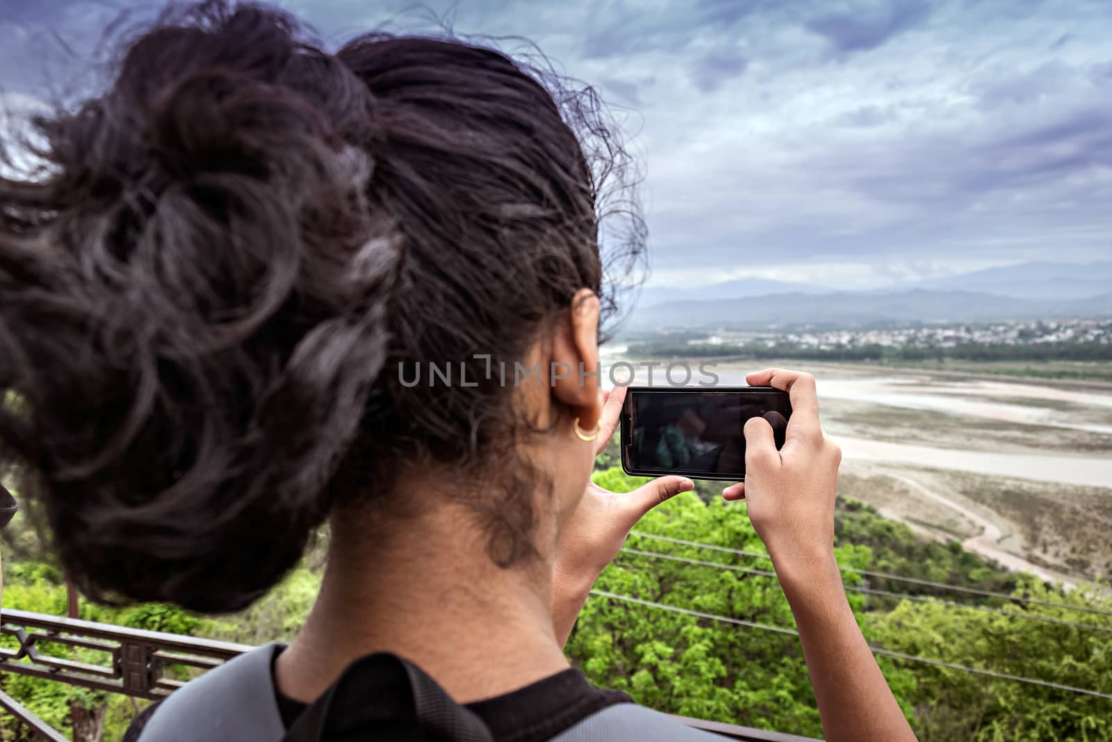 Jammu, India - April 18th, 2019 : Young lady capturing a nature scene with her cell phone.