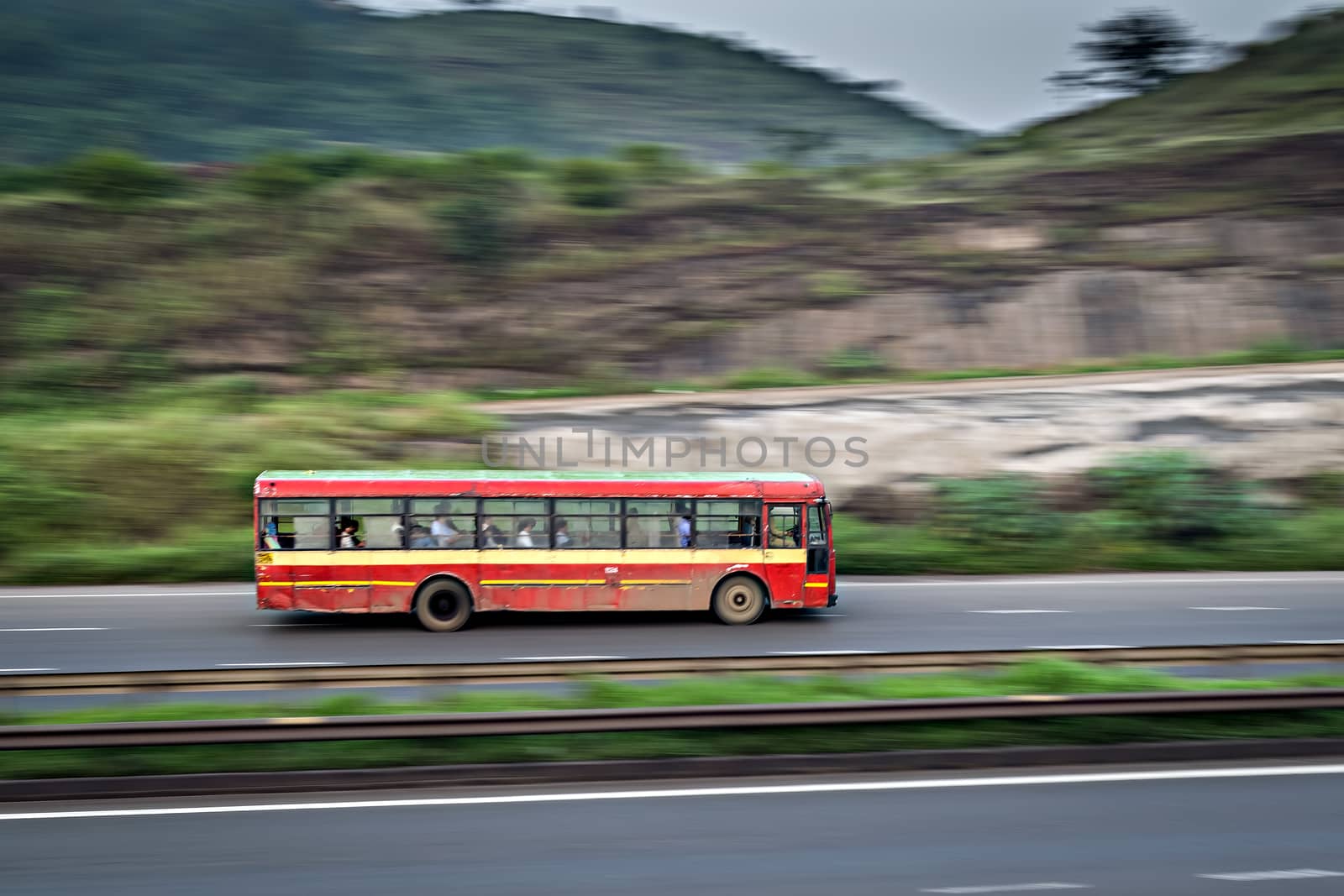 Red colored old Pune Municiapal transport local bus , speeding on highway. by lalam