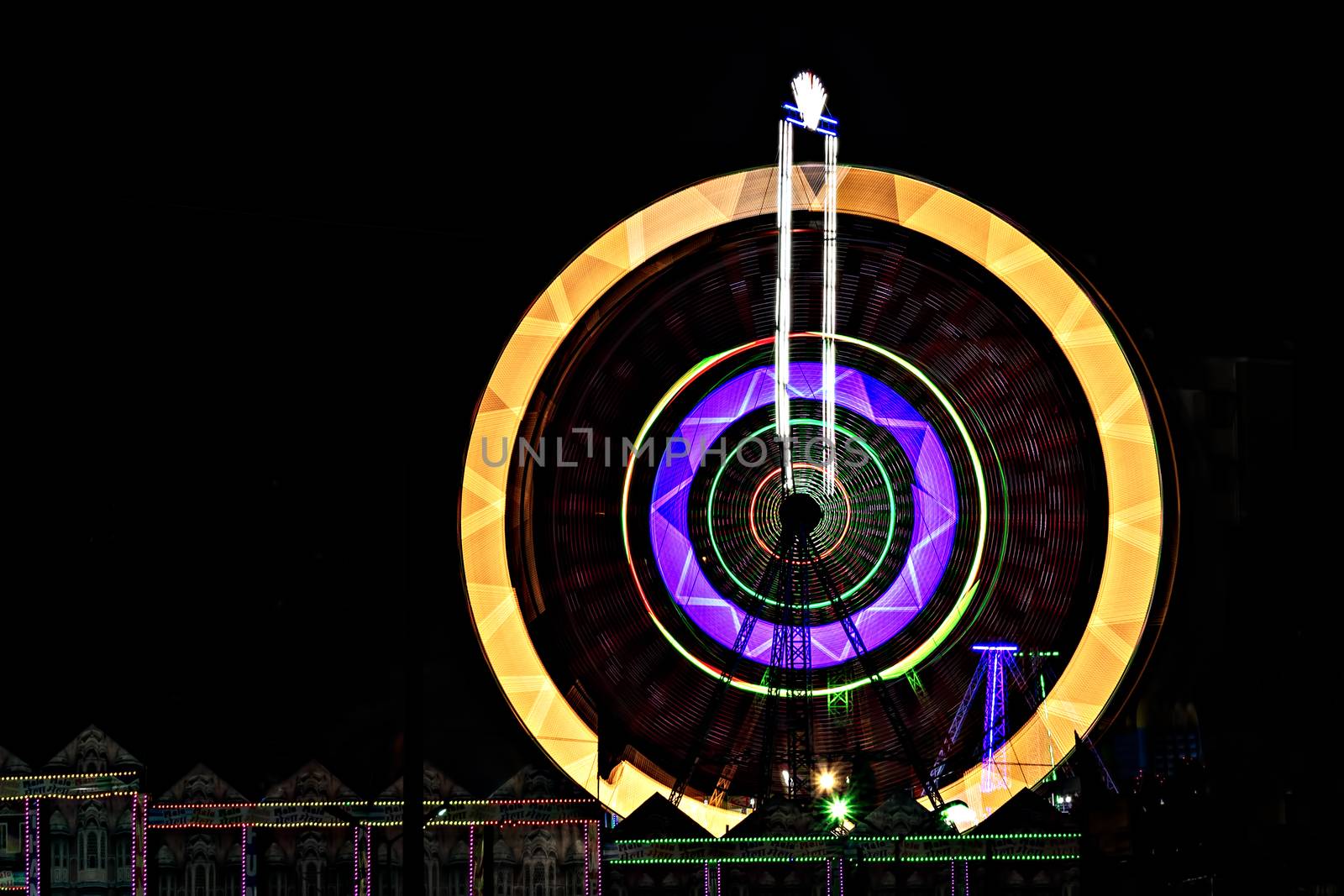 Fun fair Giant Ferris wheel spinning at night. Slow shutter photograph of a rotating giant wheel at night. by lalam