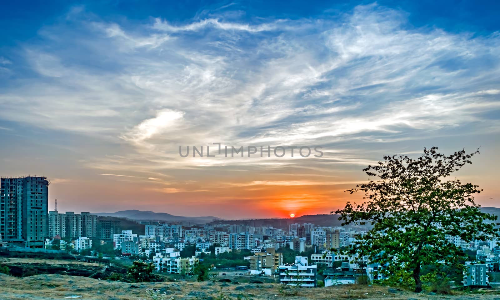 Sunset behind tall buildings in a rapidly growing city-Pune, Maharashtra, India. by lalam