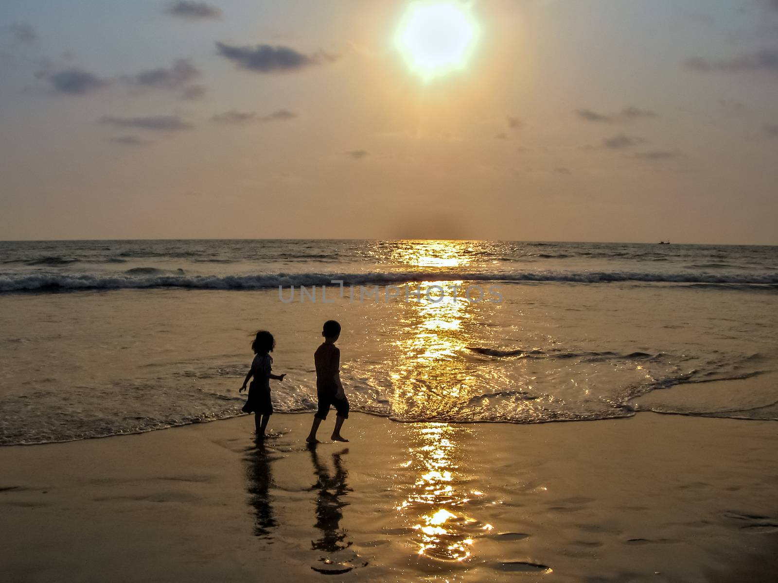 Sillhoutte image of a boy and a girl playing in sea on a background of nice Sunset. by lalam