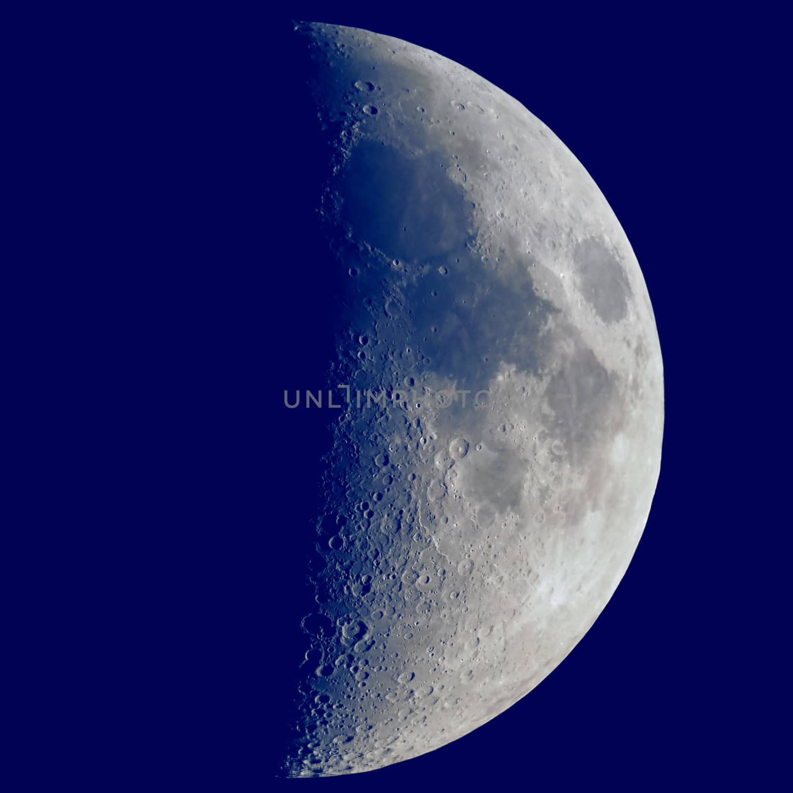 First quarter moon seen with an astronomical telescope, dark blue sky in square format