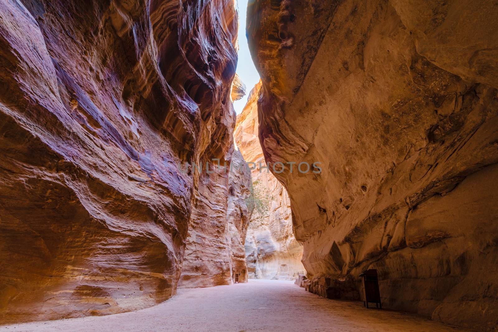 The Siq, or corridor, is a sandstone geological canyon formation leading to the archeological park of Petra, with iconic stone carved temples and tombs in Jordan, Middle East
