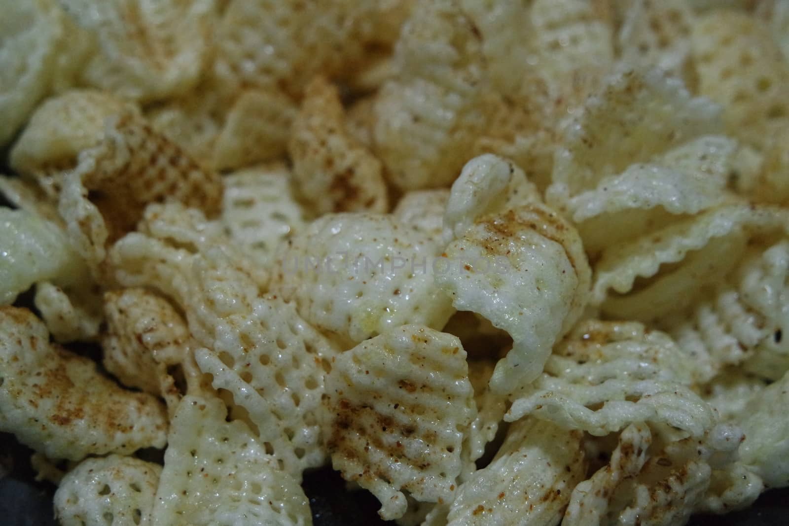 Closeup view of freshly fried chips as fast food for tea break. Potato chips with spices sprinkled on it. Fast food background for advertisements.