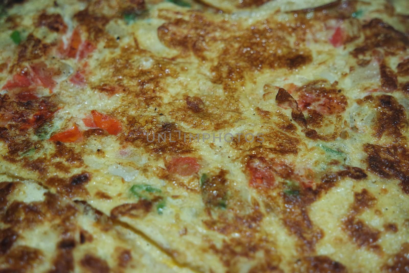 Close-up view with selective focus of egg omelet with peppers and spices sprinkled