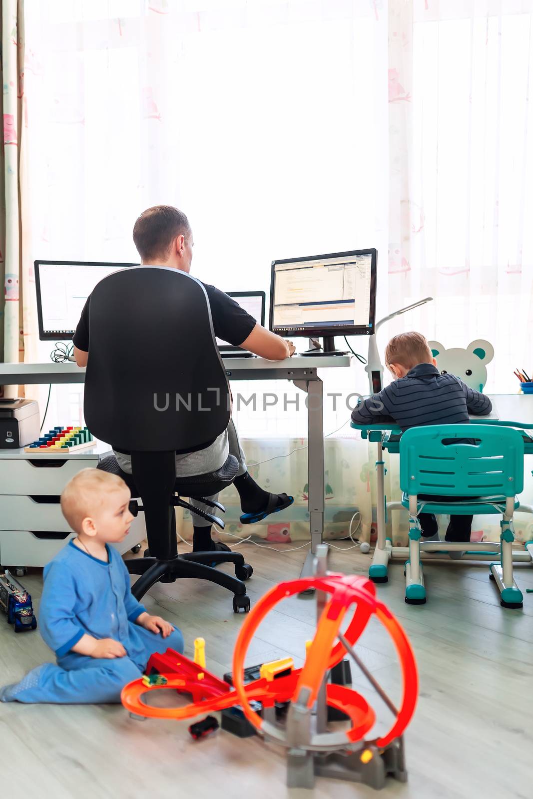 Father with kids trying to work from home during quarantine. Stay at home, work from home concept during coronavirus pandemic