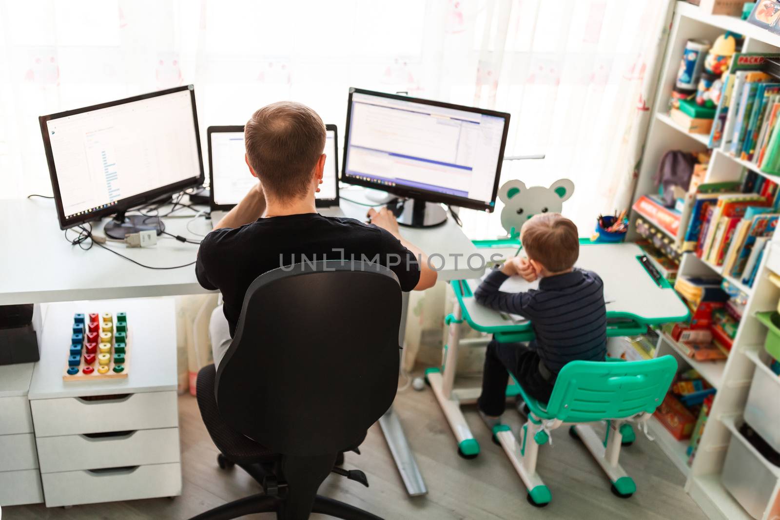 Father with kid trying to work from home during quarantine. Stay at home, work from home concept during coronavirus pandemic