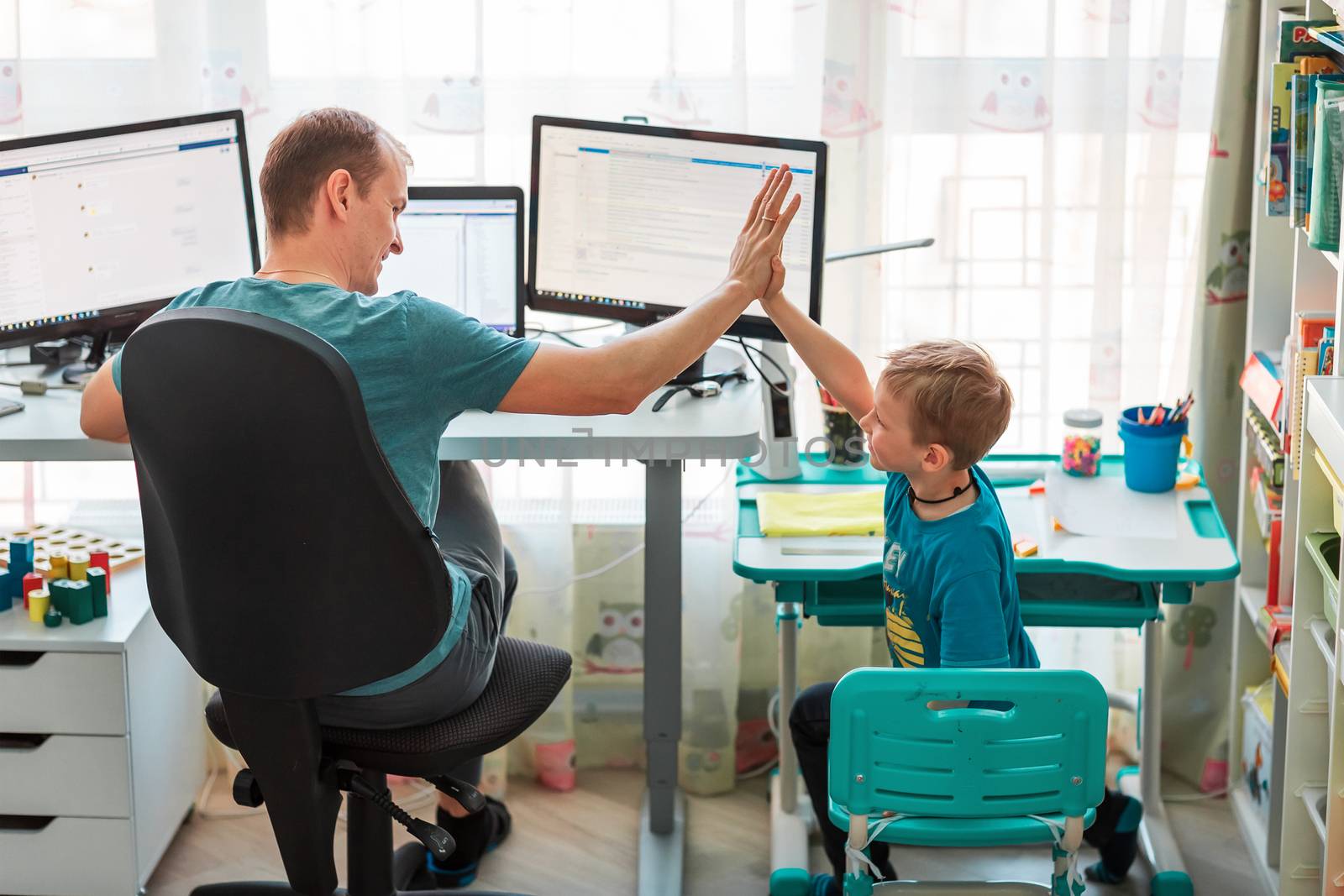 Father with kid trying to work from home during quarantine. Stay at home, work from home concept during coronavirus pandemic