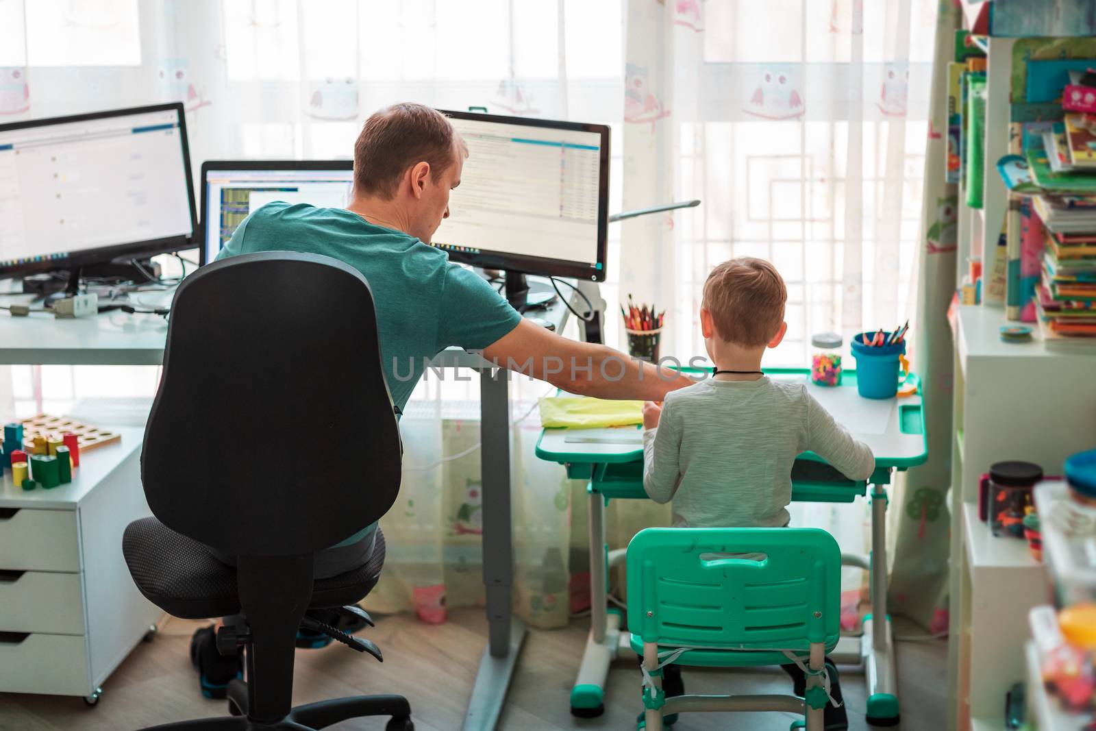 Father with kid trying to work from home during quarantine. Stay at home, work from home concept during coronavirus pandemic