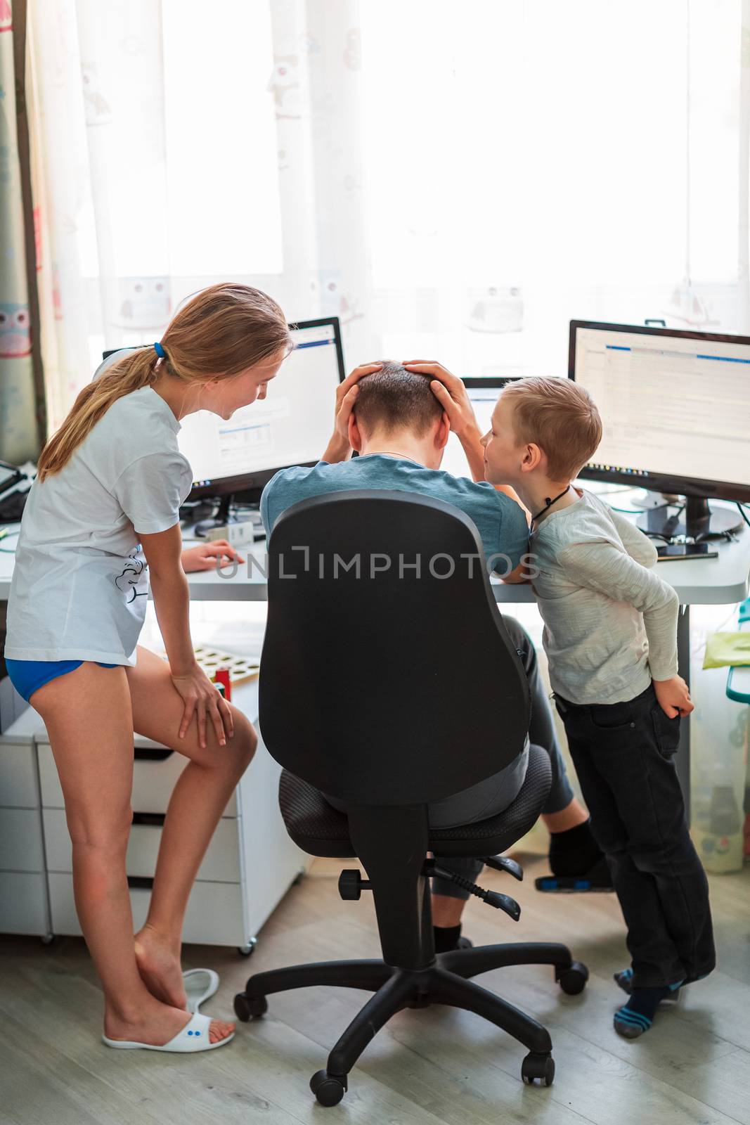 Father with kids trying to work from home during quarantine. Stay at home, work from home concept during coronavirus pandemic