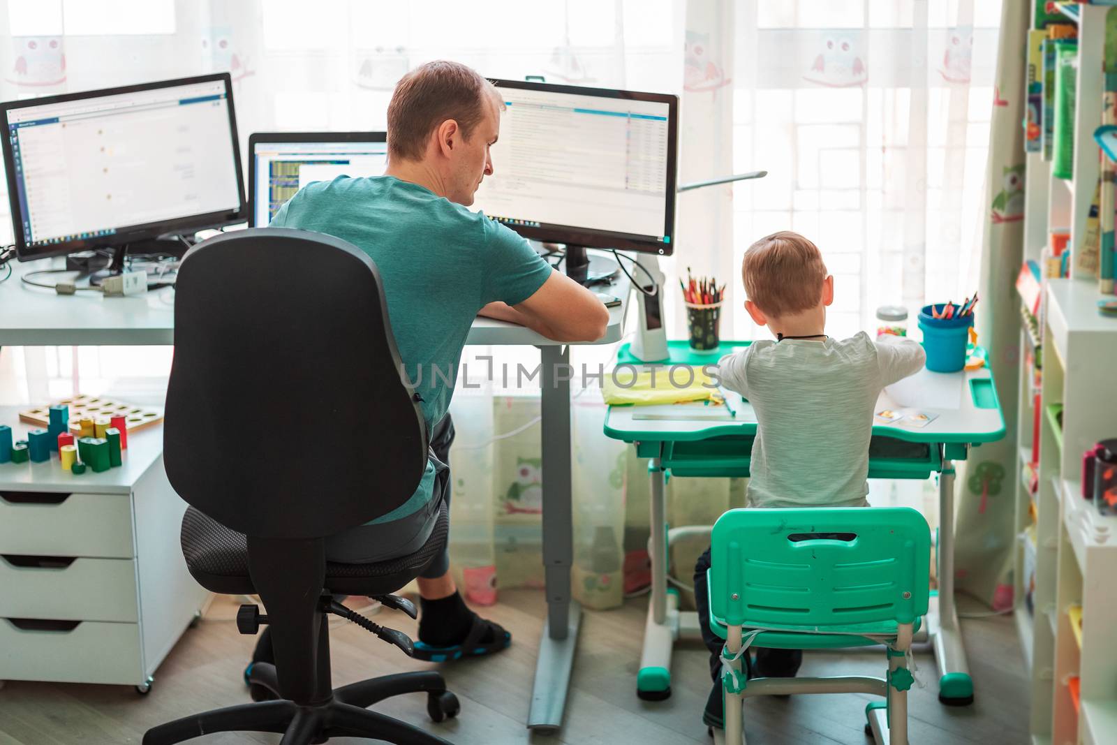 Father with kid trying to work from home during quarantine. Stay at home, work from home concept during coronavirus pandemic