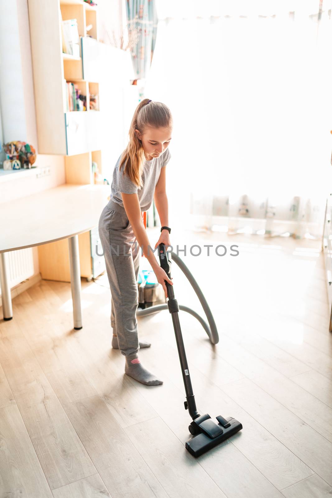 Teenage girl cleaning her room with vacuum cleaner. Children's tidiness and housekeeping help concept